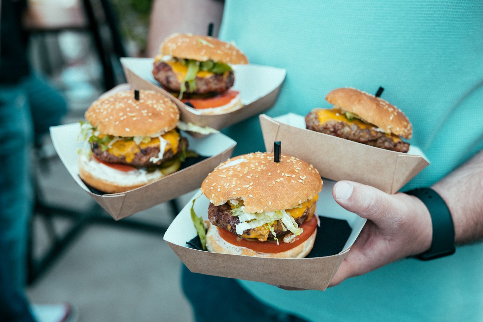 Four burgers in kraft trays carried away from a van