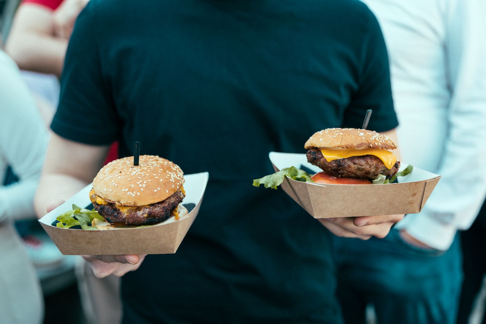 Two burgers in kraft trays carried through a festival crowd