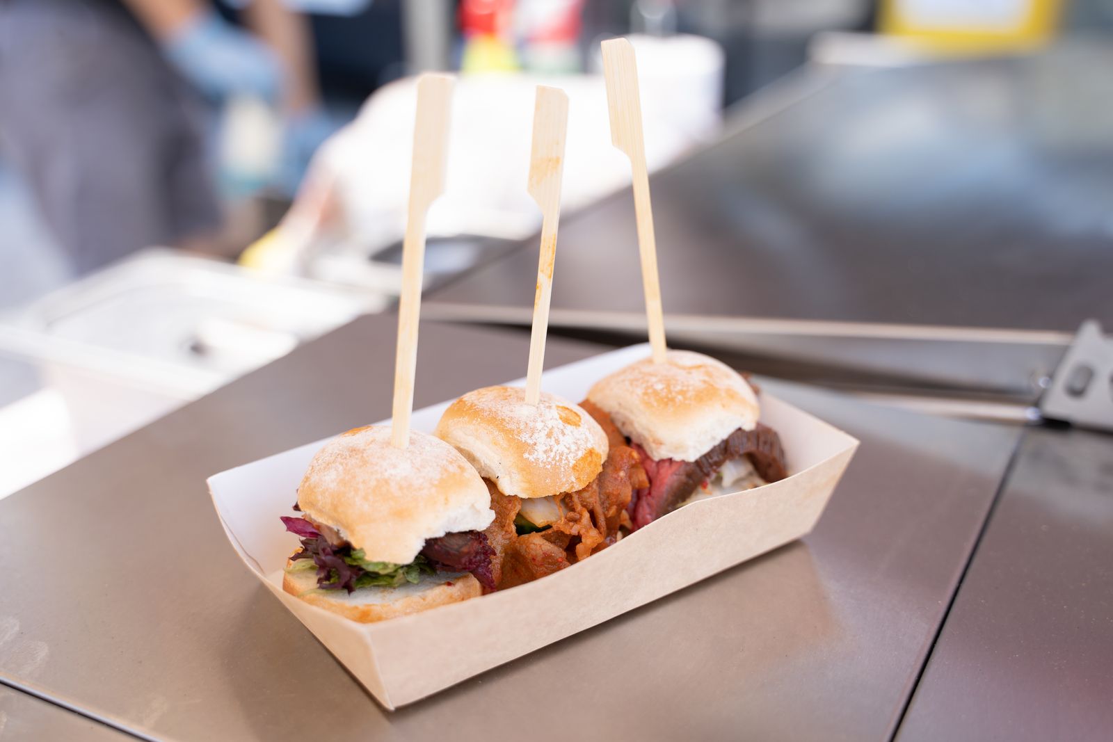 Three sliders in a kraft tray on a food truck counter